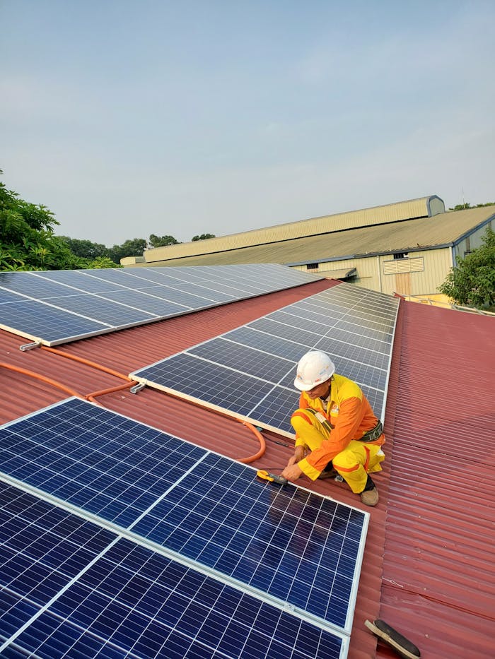 home-img Technician working on solar panel installation on a rooftop under clear sky.